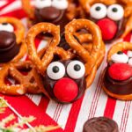 Festive reindeer Rolo pretzels are crafted with care, using pretzels, chocolate candies, and candy eyes, all delightfully arranged on a red and white striped napkin.