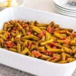 A white baking dish filled with crack green beans and pieces of bacon sits on a cooling rack.