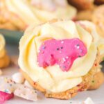 Circus animal sugar cookies topped with buttercream frosting and adorned with pink and white animal-shaped sprinkles.