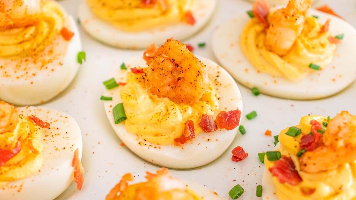 A platter with deviled eggs with shrimp and bacon.