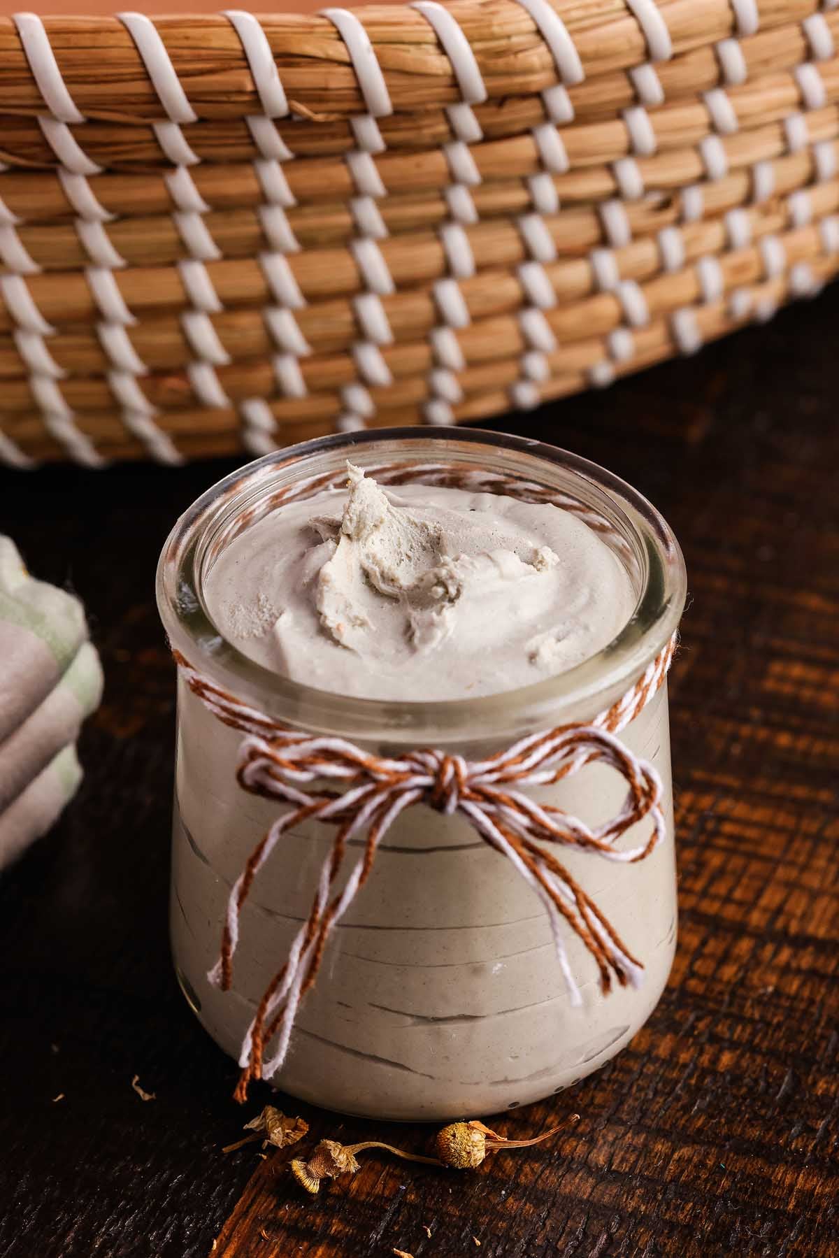 A small jar of homemade diaper rash cream on a wooden surface.
