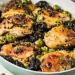 Savor the rich flavors of chicken Marbella with succulent thighs, olives, and prunes in a pan, perfectly garnished with herbs.