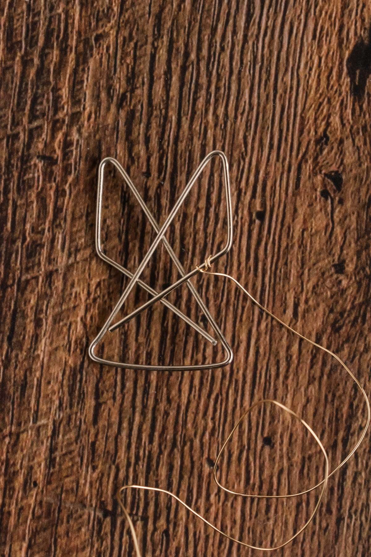 Two intertwined paperclips with a thin wire on a wooden surface.