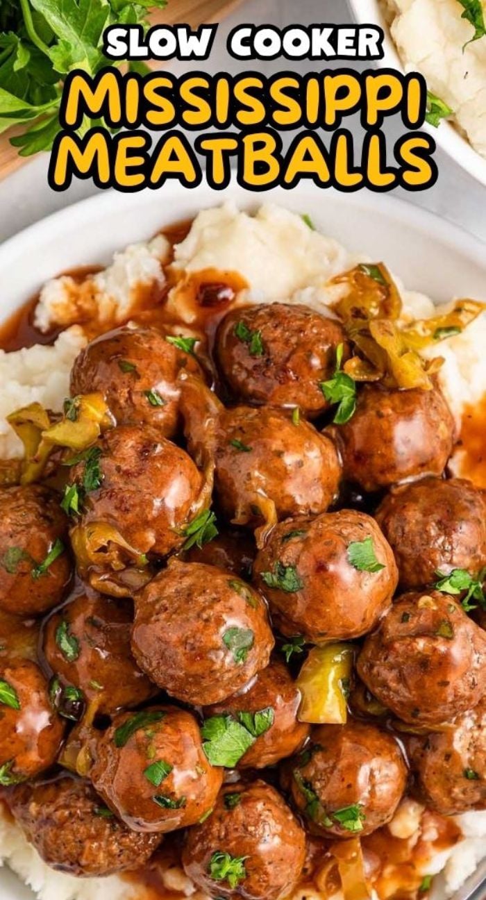 A plate of slow cooker Mississippi meatballs in sauce served over mashed potatoes, garnished with herbs and peppers.