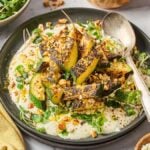 Charred zucchini salad on a creamy cottage cheese sauce, garnished with nuts and herbs, served with honey and feta.