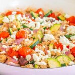 Savor the flavors of a Mediterranean Ground Chicken Skillet featuring cooked ground chicken, zucchini slices, cherry tomatoes, Kalamata olives, red onions, and crumbled feta cheese.