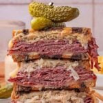 The classic Reuben sandwich features layers of corned beef, sauerkraut, and melted cheese, all nestled between slices of rye bread and topped with tangy pickles.