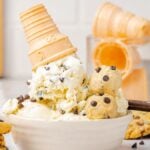 Vanilla no churn cookie dough ice cream in a bowl with a tipped cone, rich chocolate chip cookie dough, and chocolate chip cookies.