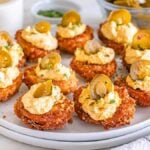 A plate of fried deviled eggs topped with creamy filling and jalapeño slices, garnished with herbs.