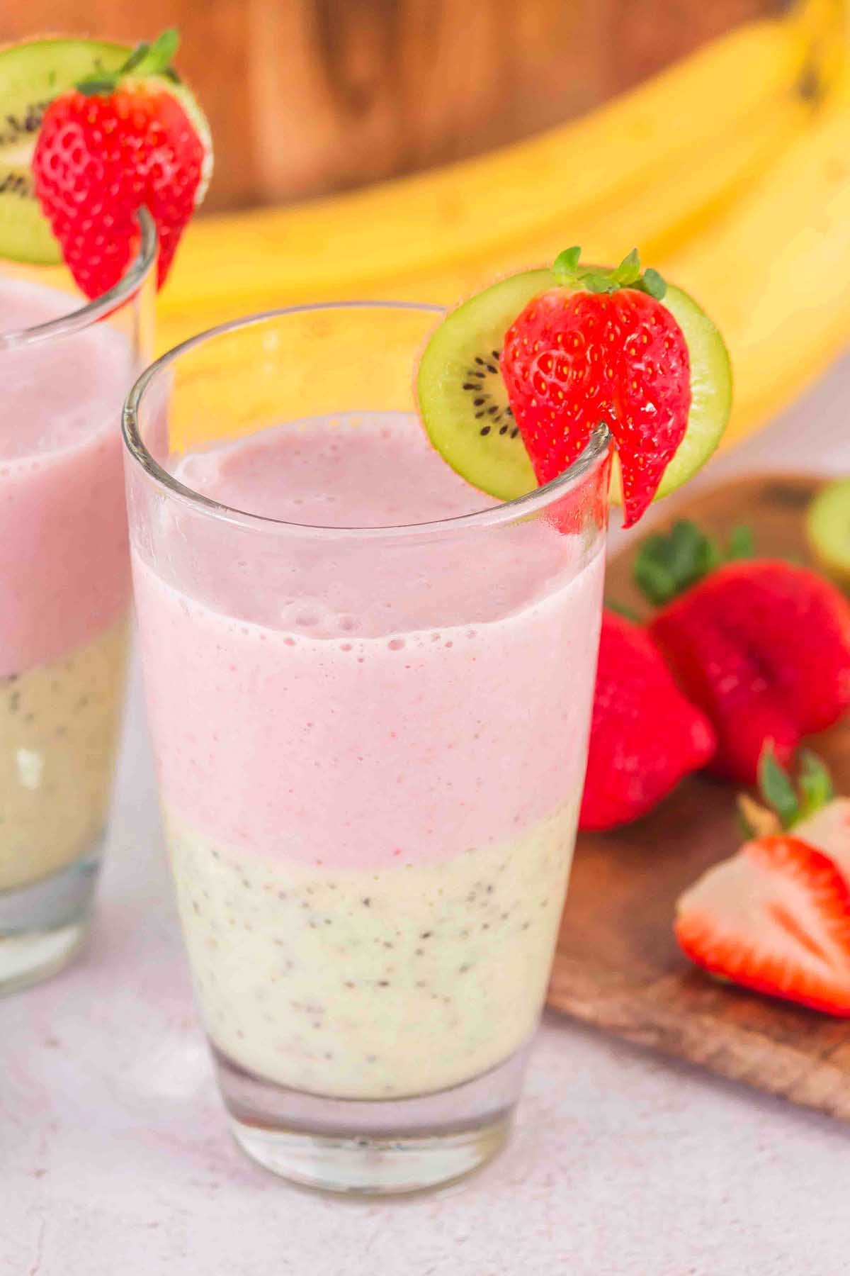 Layered Kiwi Strawberry Smoothie in a glass, garnished with a fresh kiwi slice and strawberry on the rim.