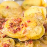 Campfire potatoes with melted cheese, bacon, and herbs are served hot from a foil-lined pan—perfect for sharing around the fire.