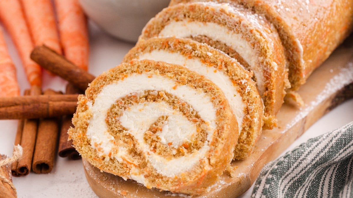 A platter with a sliced carrot cake roll. 