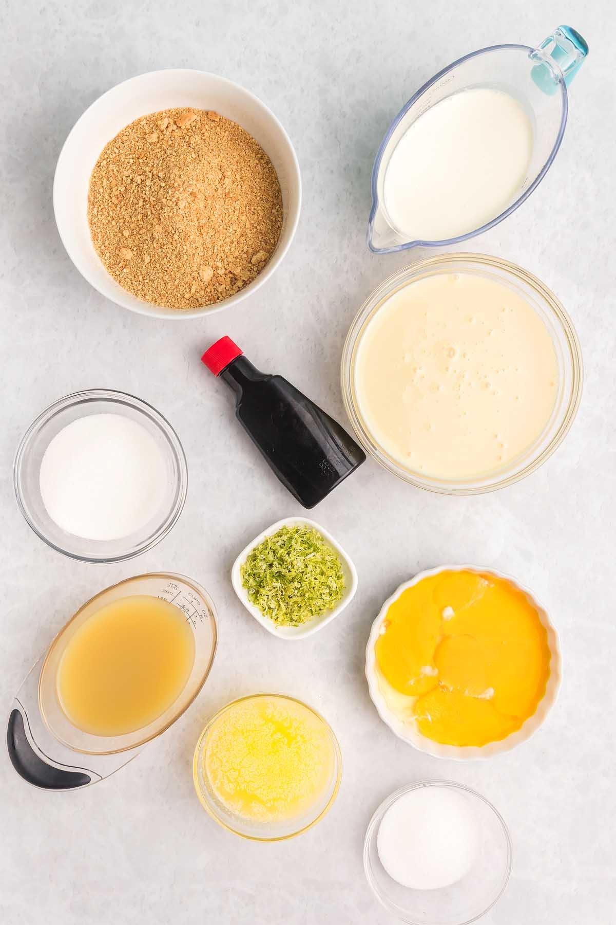 Bowl of graham crumbs, eggs, milk, sugar, zest, juice, butter, and vanilla on a light surface—ingredients ready to create delicious key lime bars.