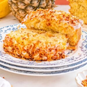Two slices of Hawaiian banana bread on a blue-patterned plate, topped with toasted coconut flakes.