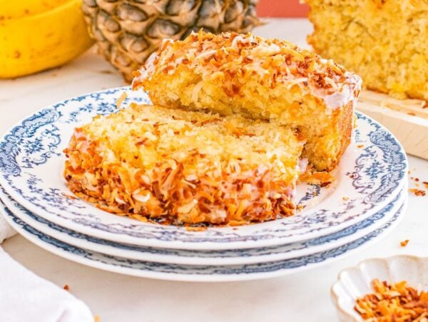 Two slices of Hawaiian banana bread on a blue-patterned plate, topped with toasted coconut flakes.