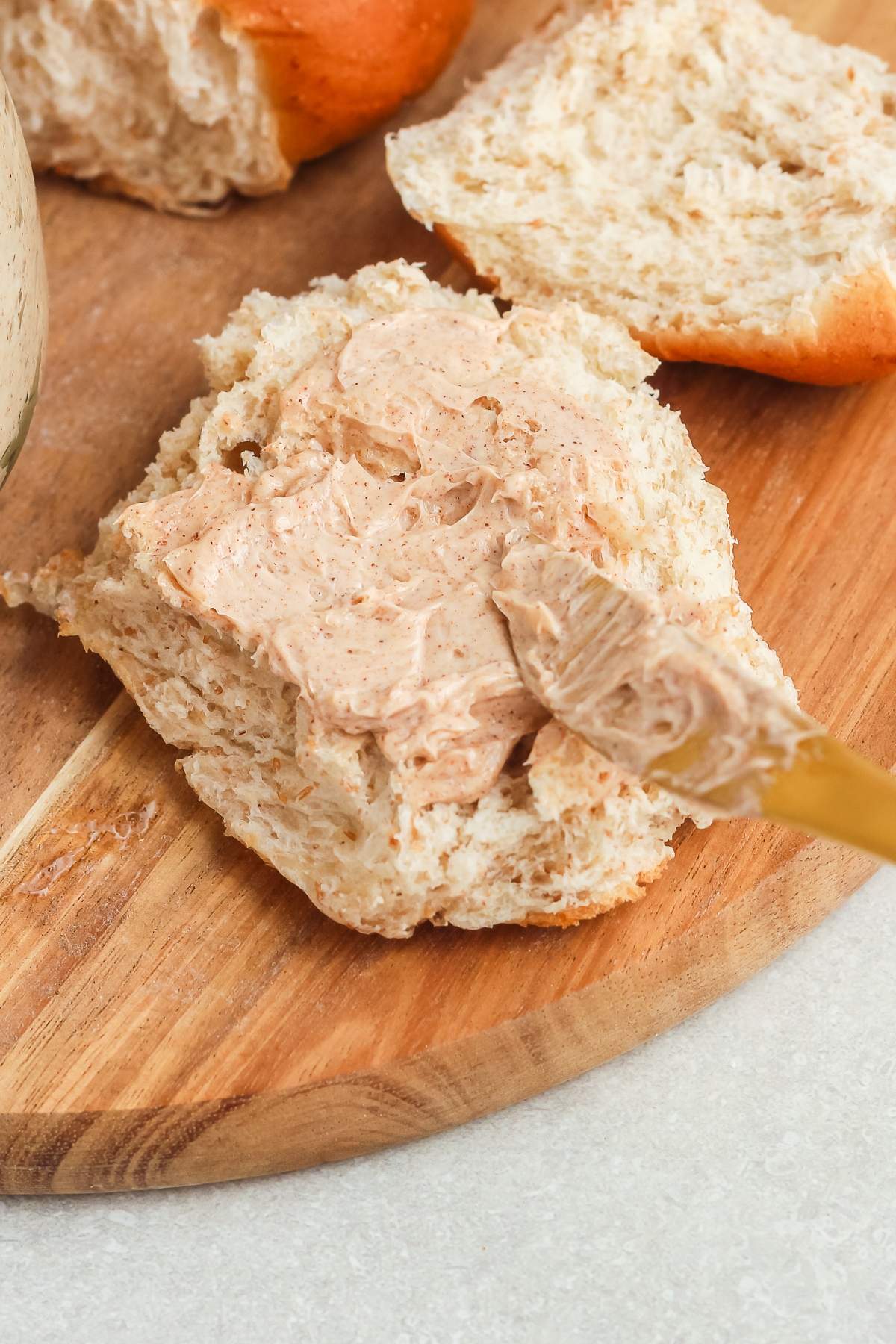 A knife spreading cinnamon butter on a piece of bread on a wooden board.