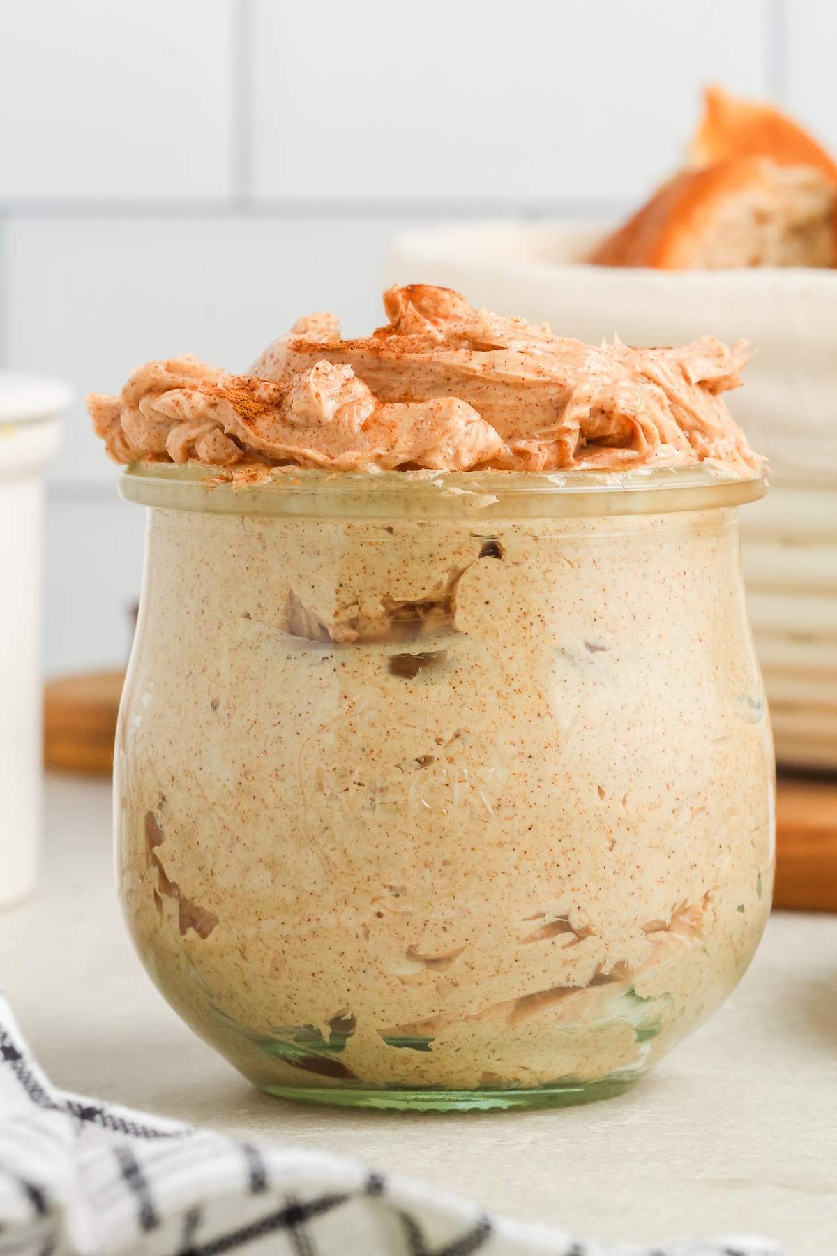 A glass jar filled with whipped cinnamon butter, with swirls visible on top.