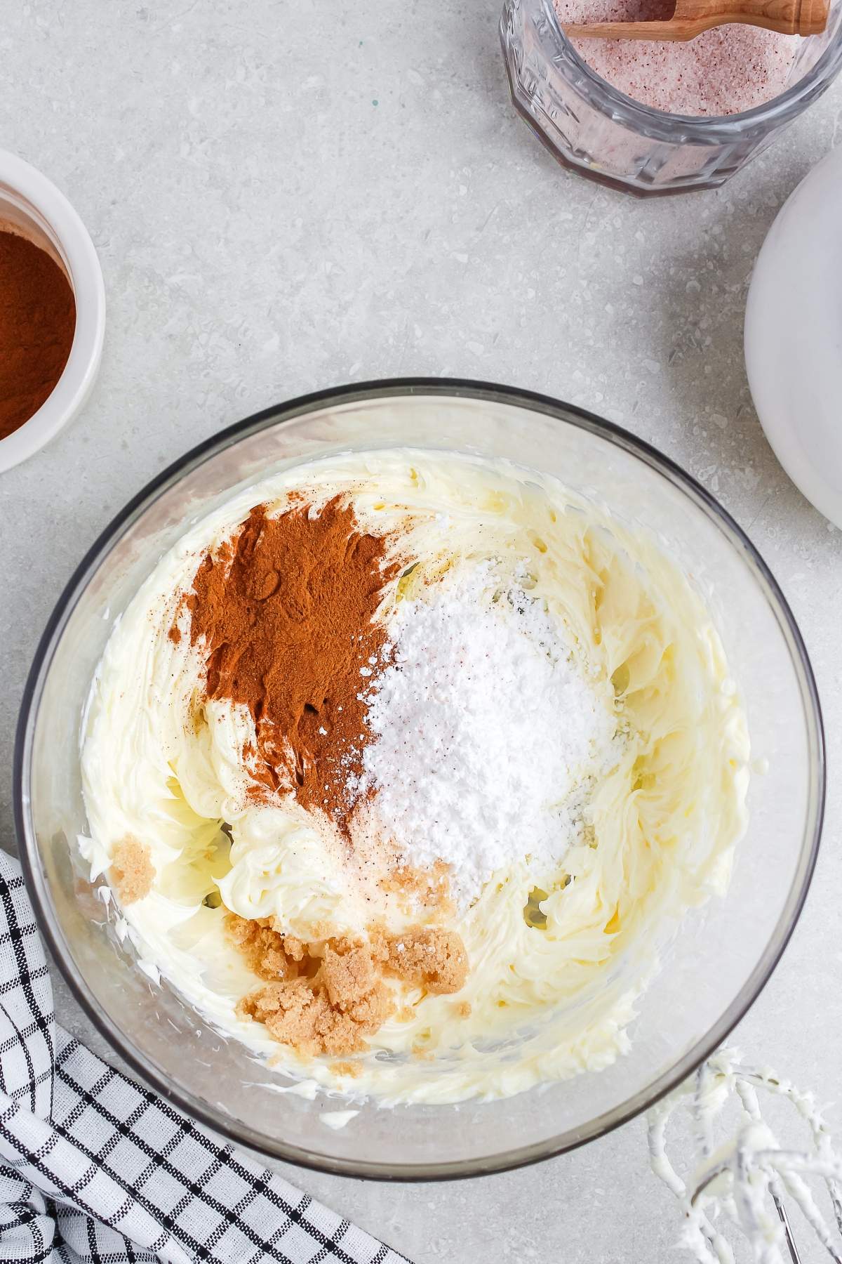 Glass bowl of whipped butter with cinnamon, powdered sugar, and brown sugar on a gray countertop.