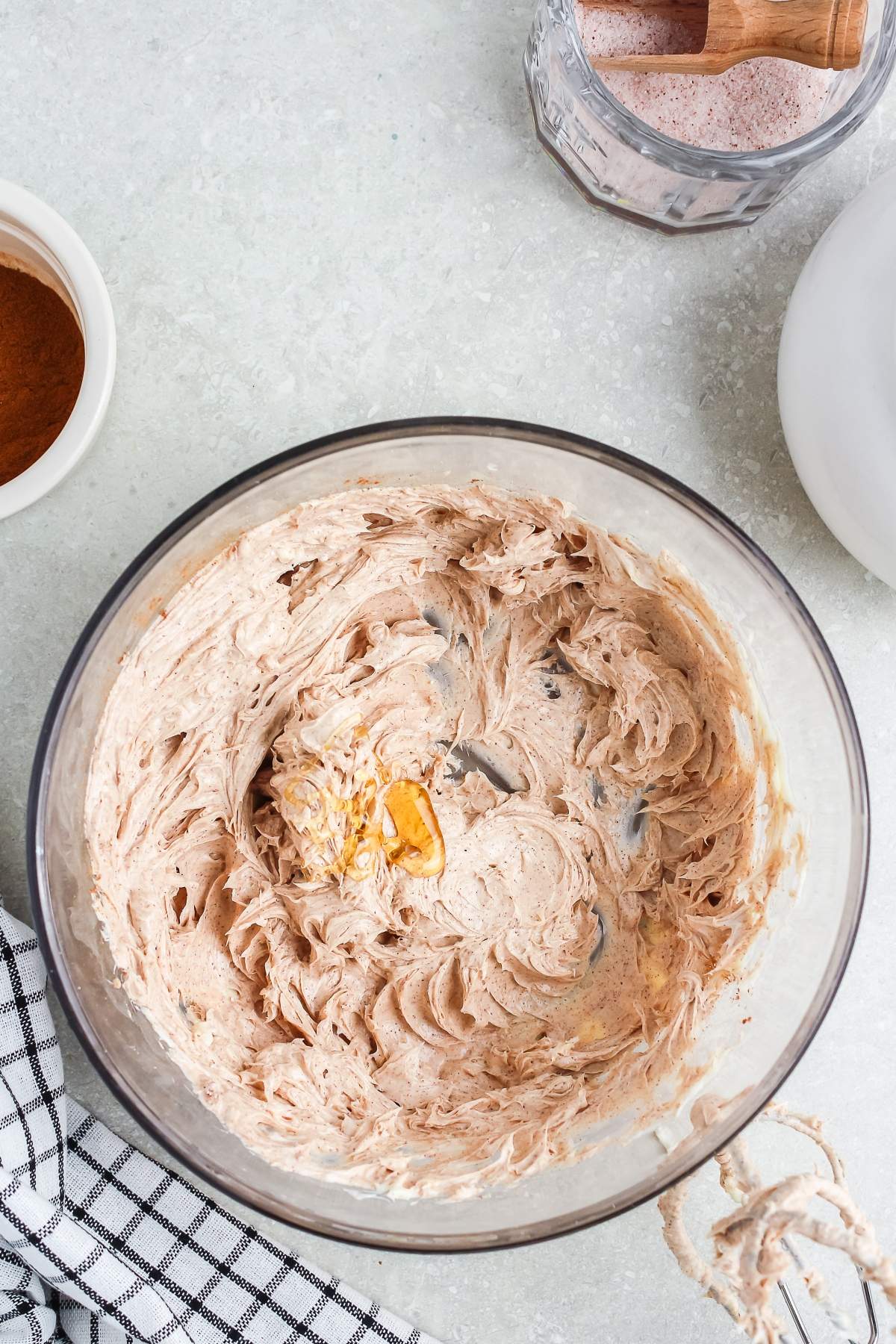 A glass bowl with creamy, whipped mixture and a raw egg yolk, surrounded by baking ingredients.