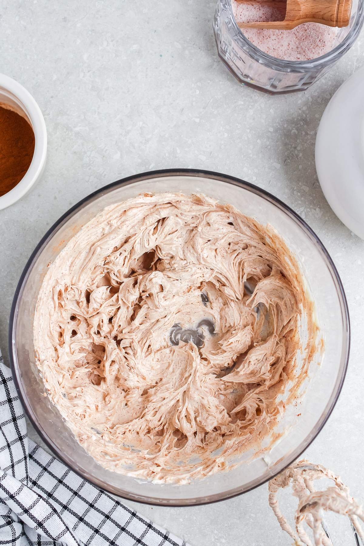 A mixing bowl of whipped cinnamon butter on a countertop with ingredients nearby.