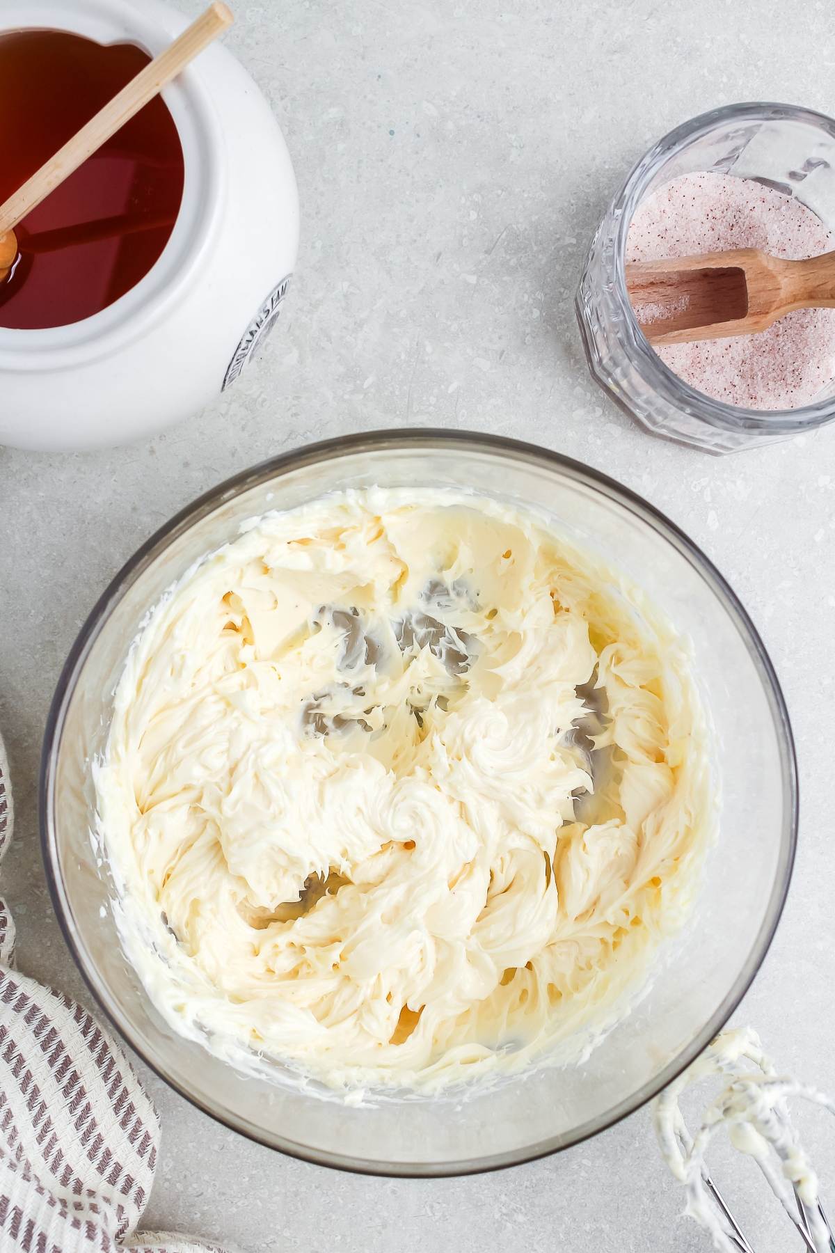 A glass bowl of whipped butter on a countertop, with honey and cinnamon sugar nearby.