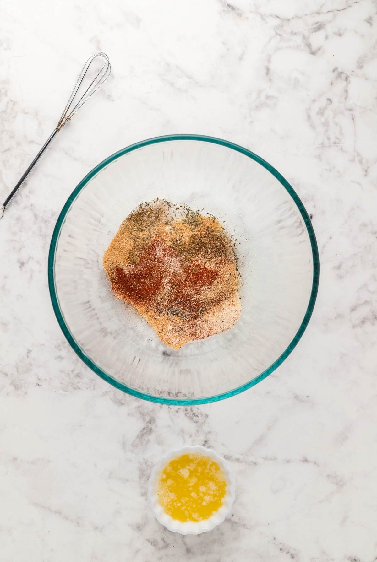 A glass bowl with spices and breadcrumbs, and a small bowl of melted butter on a marble countertop—perfect prep for your Instant Pot Blackened Chicken Alfredo or any quick pasta dinner in an instant pot.