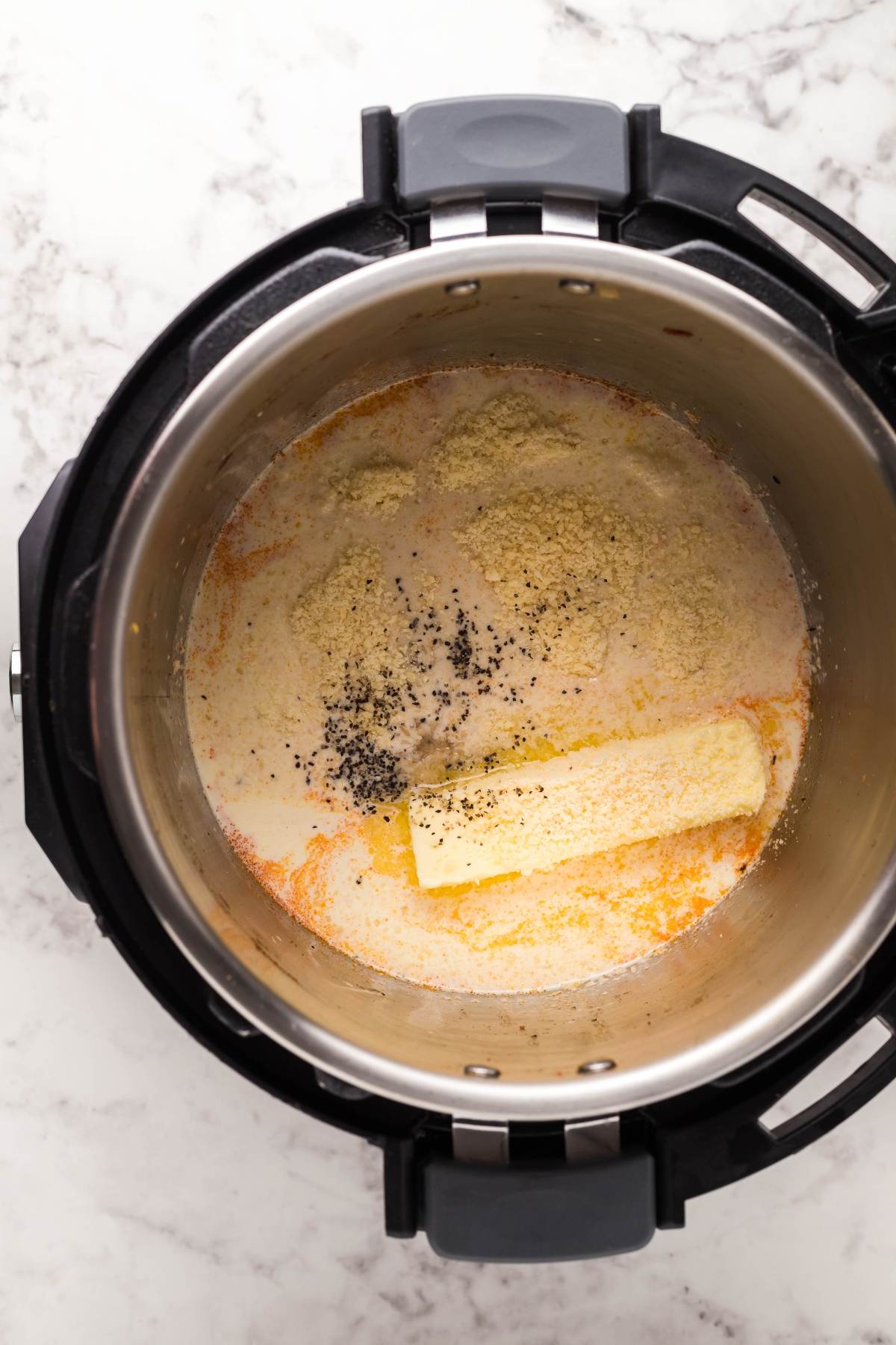 An Instant Pot with butter, seasonings, and flour mixture inside sits on a marble counter, ready to become a delicious instant pot chicken pasta dinner.