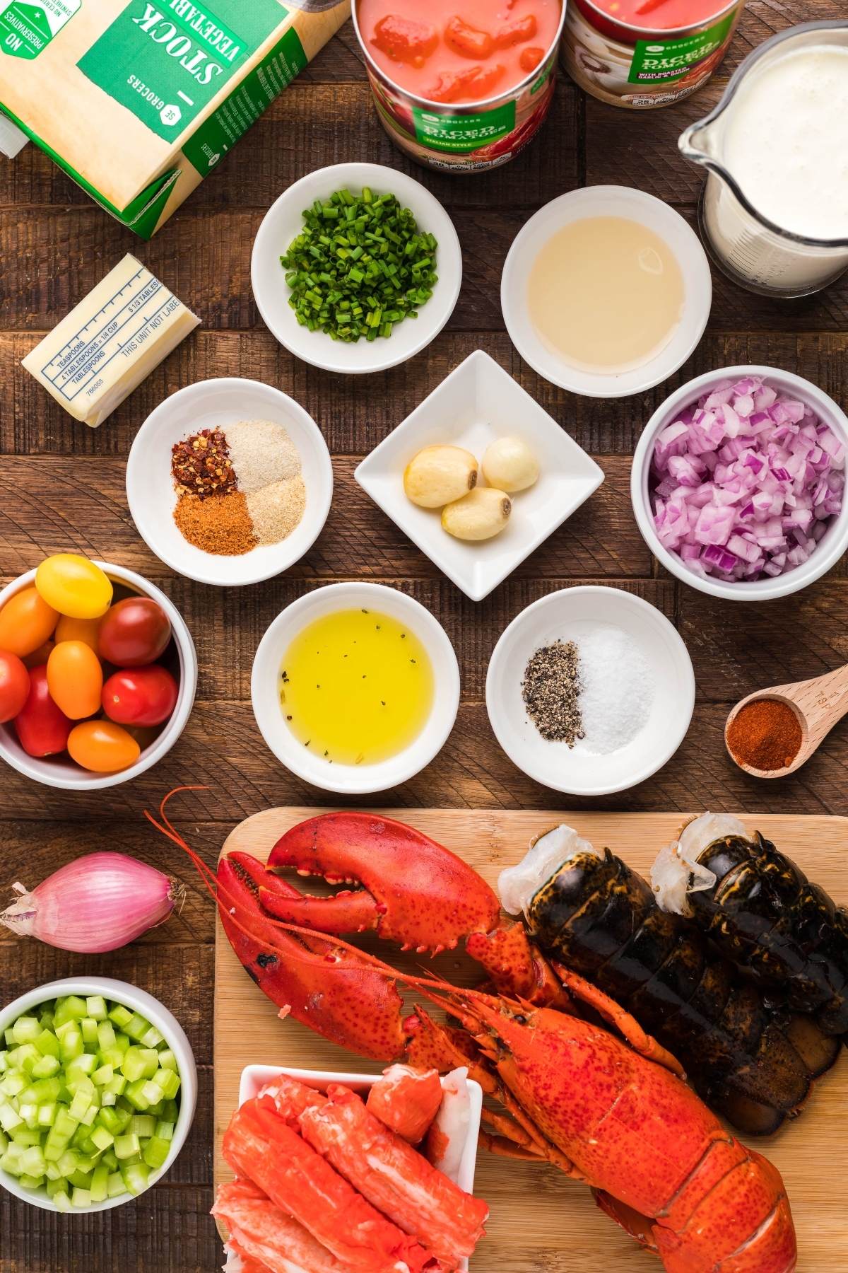 Assorted seafood, vegetables, and seasonings arranged on a wooden surface for cooking preparation—perfect ingredients for the best bisque recipe or a Slow Cooker Seafood Bisque.