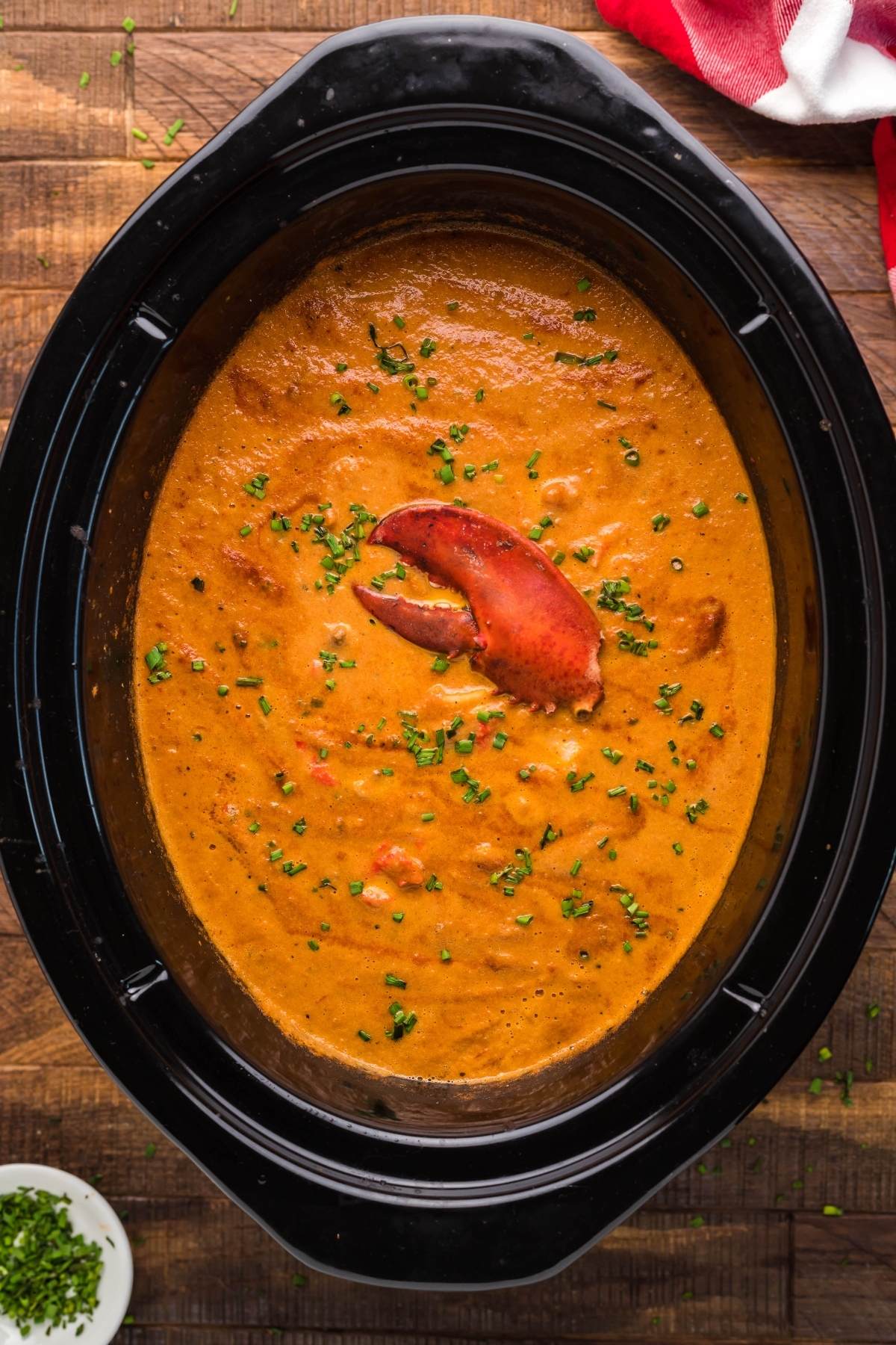 Savor this creamy seafood soup—Lobster Bisque in a slow cooker, garnished with chives and a lobster claw on top. The best bisque recipe for effortless gourmet flavor at home.