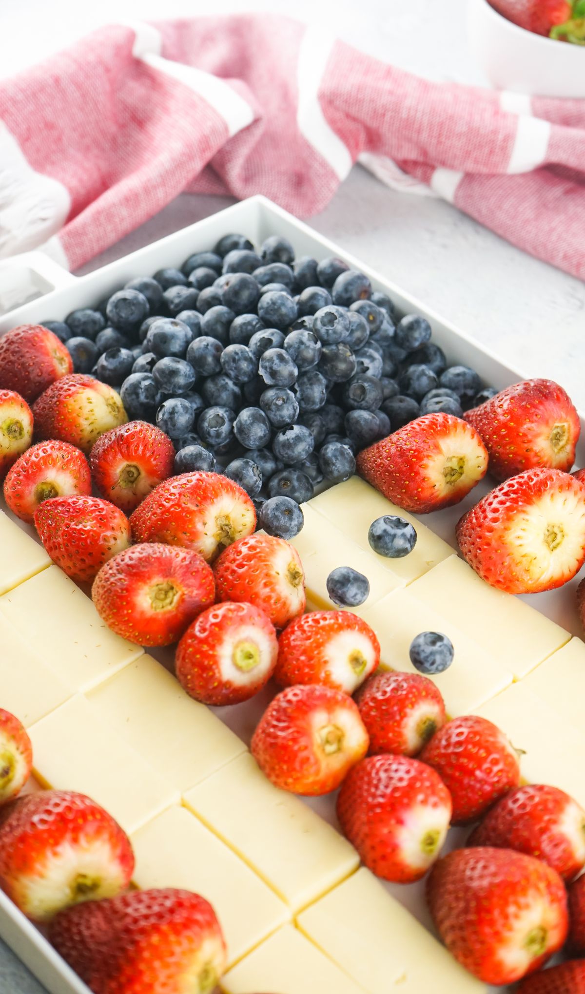 A Stars and Stripes Cheese Board features a tray with rows of strawberries, blueberries, and cheese slices, with a red and white towel nearby.