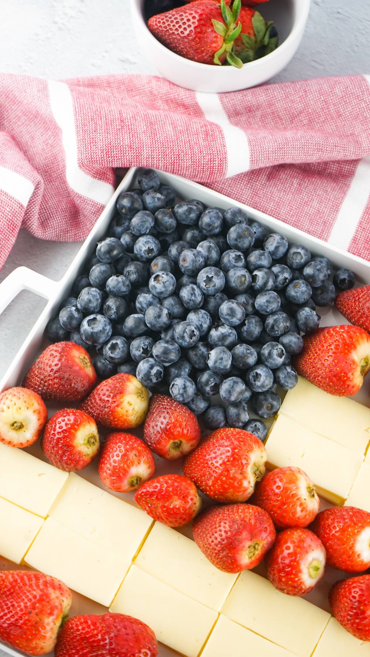 Rectangular tray with blueberries, strawberries, and cheese arranged to resemble an American flag.