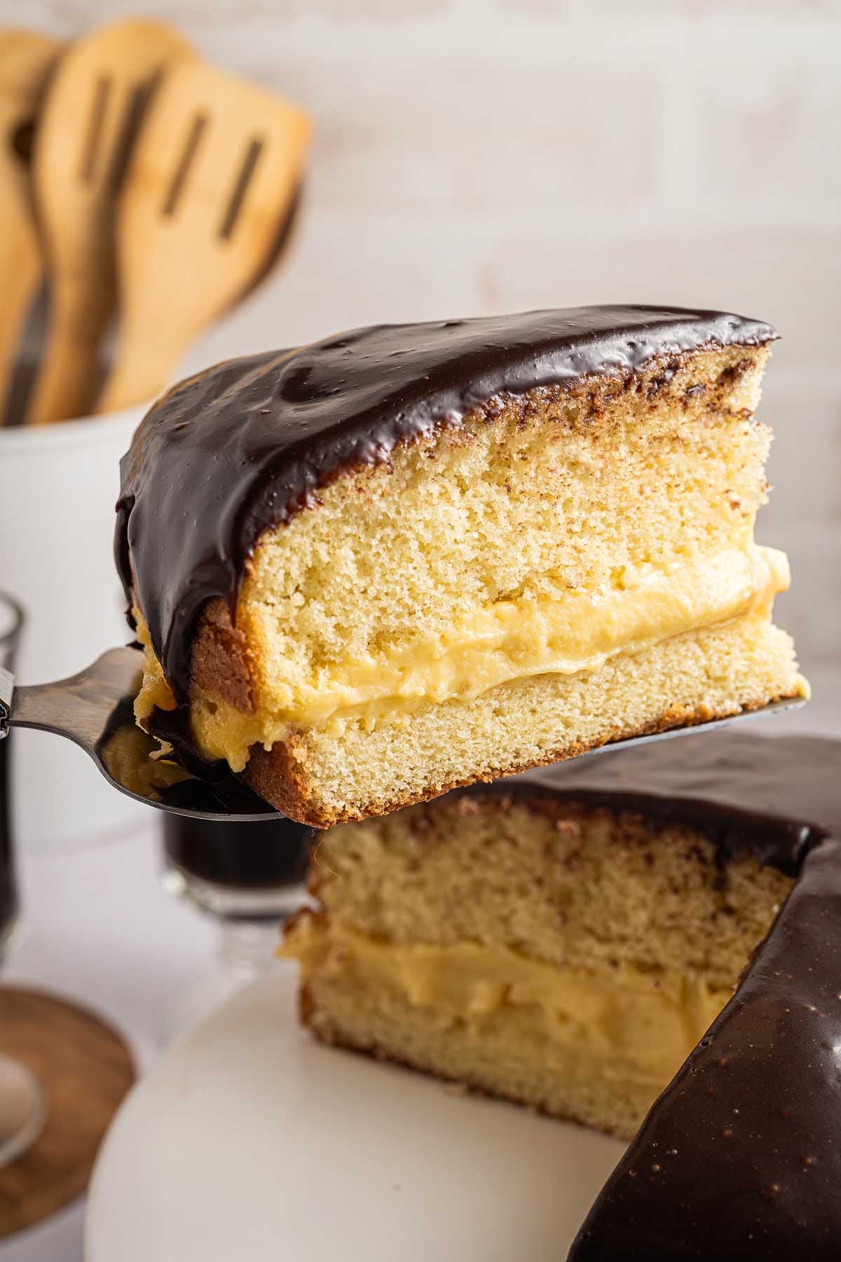 A classic Boston cream pie slice with luscious yellow custard filling and a glossy chocolate glaze on top.