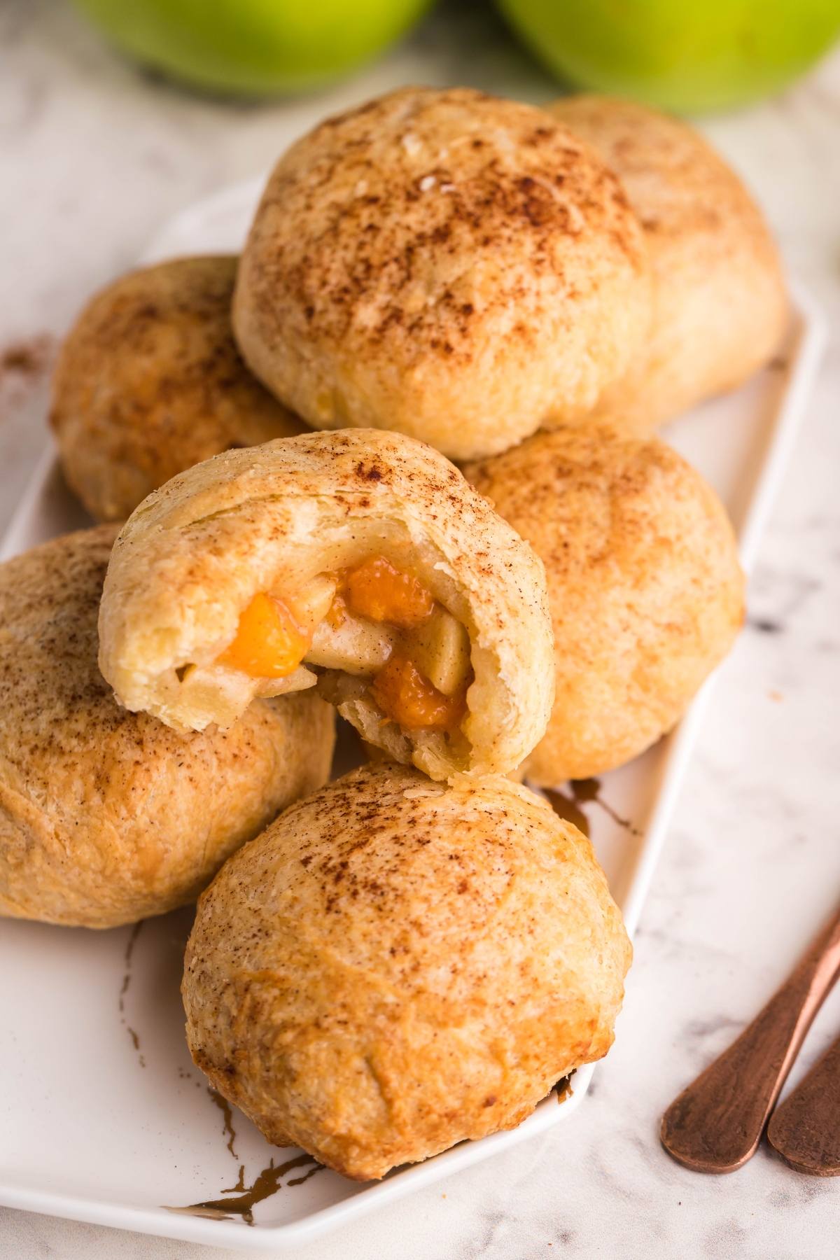 A plate of puff pastry dumplings, with one revealing a sweet apple filling inside. Perfect as Air Fryer Apricot Apple Dumplings for a delicious twist on classic air fryer dumplings.