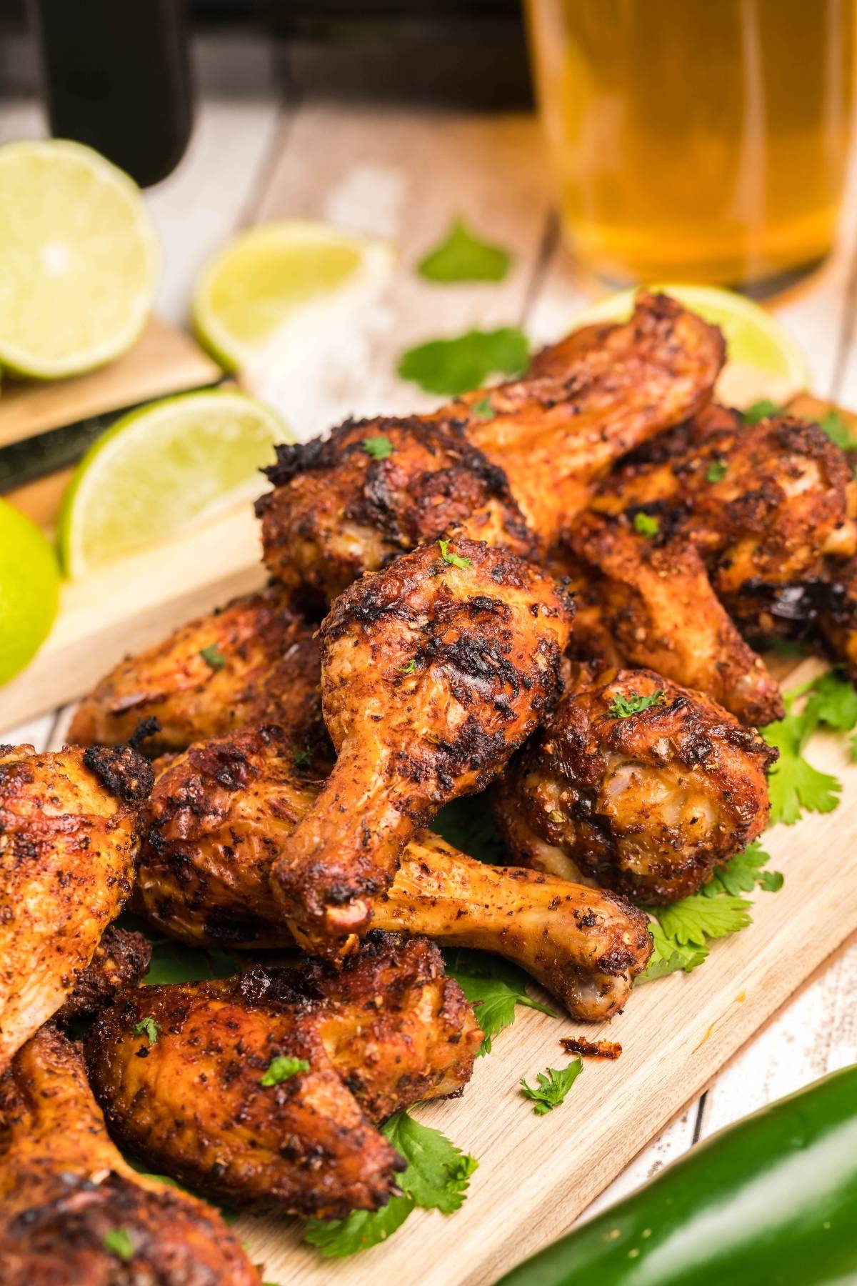 Grilled chicken drumsticks on a wooden board, garnished with cilantro and served with lime slices—perfect when paired with homemade firecracker ranch dressing.