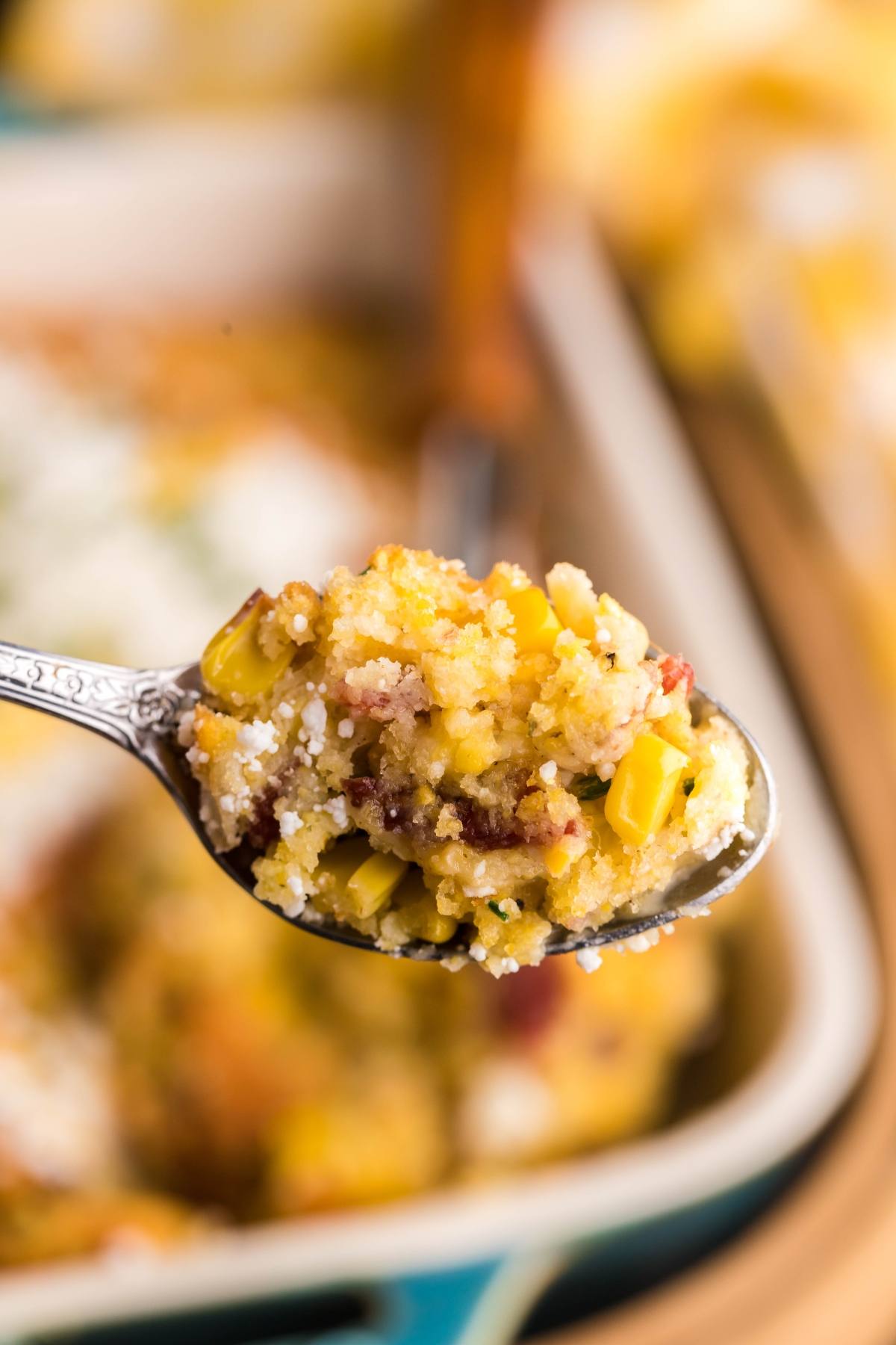 A close-up of a spoonful of cornbread casserole made with Jiffy cornbread mix, featuring corn and bits of bacon—perfect for those craving the best corn casserole.