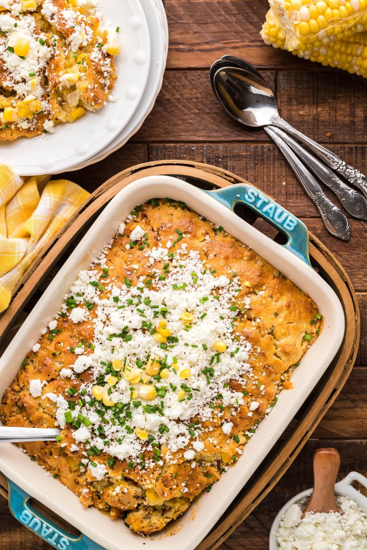 Baked Mexican street corn casserole topped with cheese and herbs in a blue dish, with a serving scooped out—this is truly the best corn casserole for sharing at any gathering.