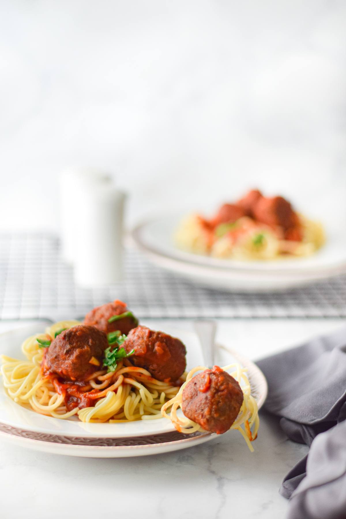 Vegan meatballs with spaghetti marinara and tomato sauce garnished with herbs, served on a white plate.