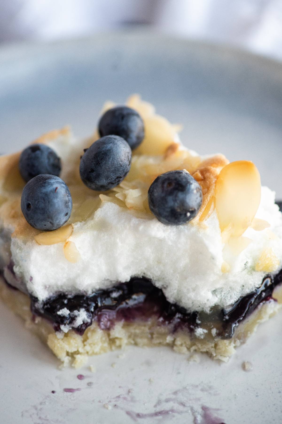 A dessert bar with a crumbly base, blueberry filling, meringue topping, sliced almonds, and fresh blueberries—these Blueberry Pie Meringue Squares are an easy blueberry dessert recipe perfect for any occasion.