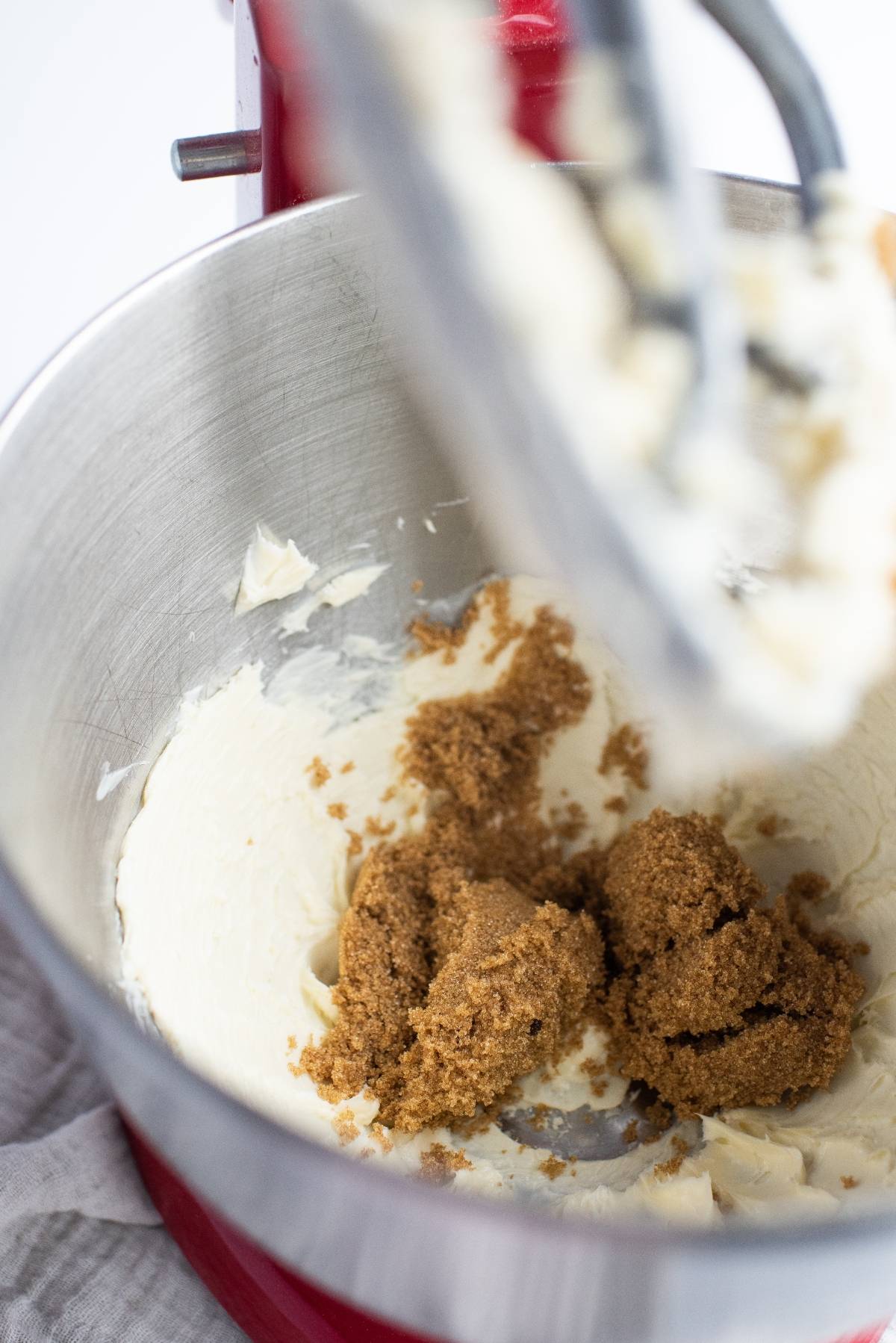 Brown sugar and creamed butter in a metal mixing bowl of a red stand mixer, ready to create delicious almond and blueberry cookie bars.