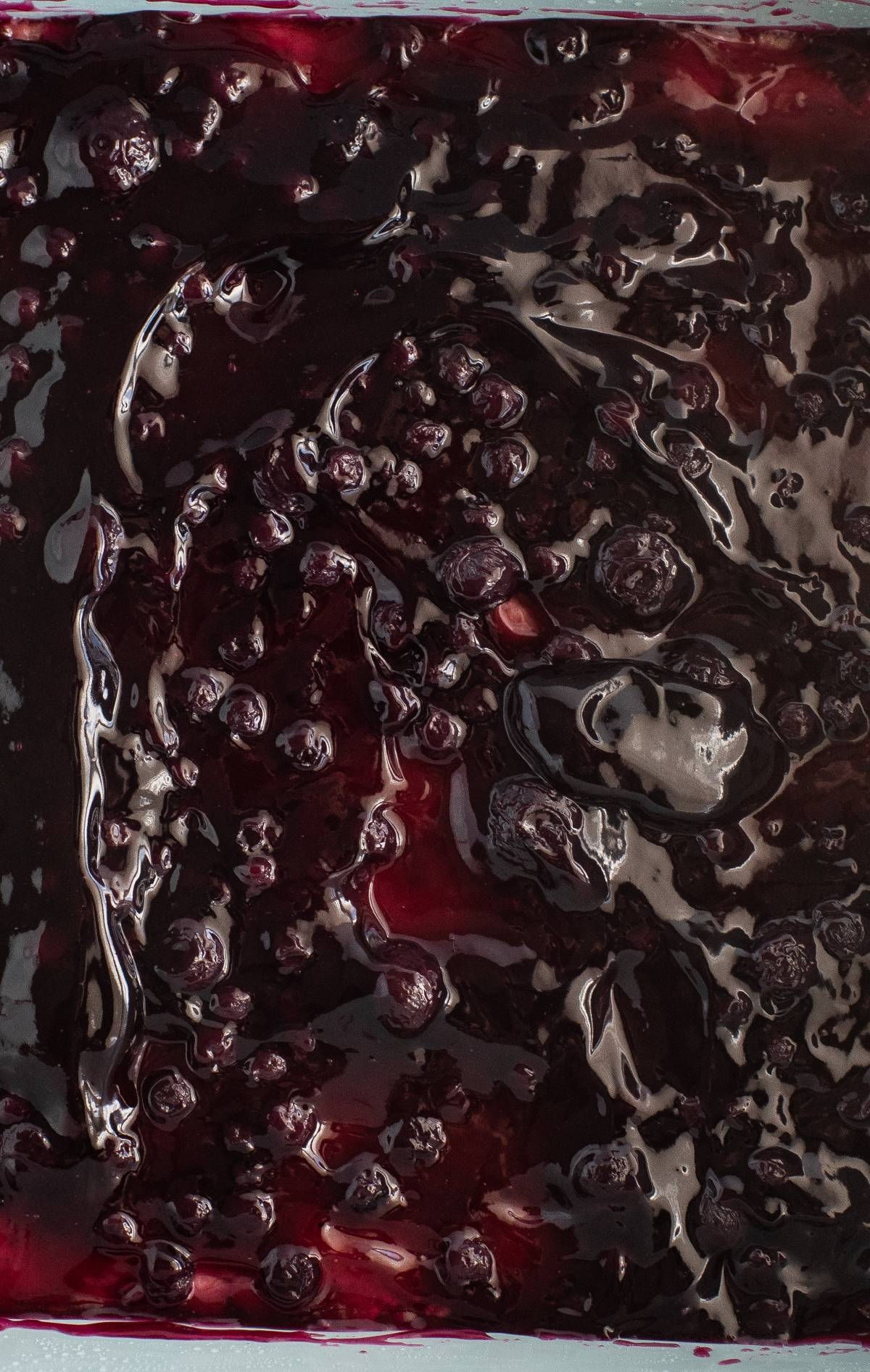 Close-up of glossy blueberry pie filling with whole berries and thick, dark purple syrup—perfect for an easy blueberry dessert recipe or as a delicious base in your favorite bar recipe with meringue.