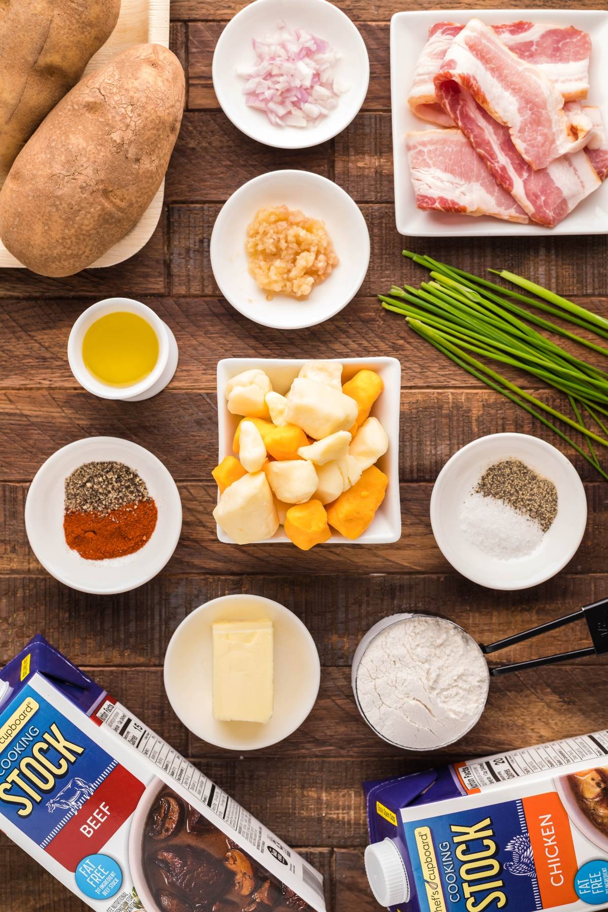 Overhead view of raw soup ingredients: potatoes, bacon, cheese, seasonings, stock, oil, butter, and chives—perfect for anyone curious about how to make poutine or searching for the best poutine gravy recipe.