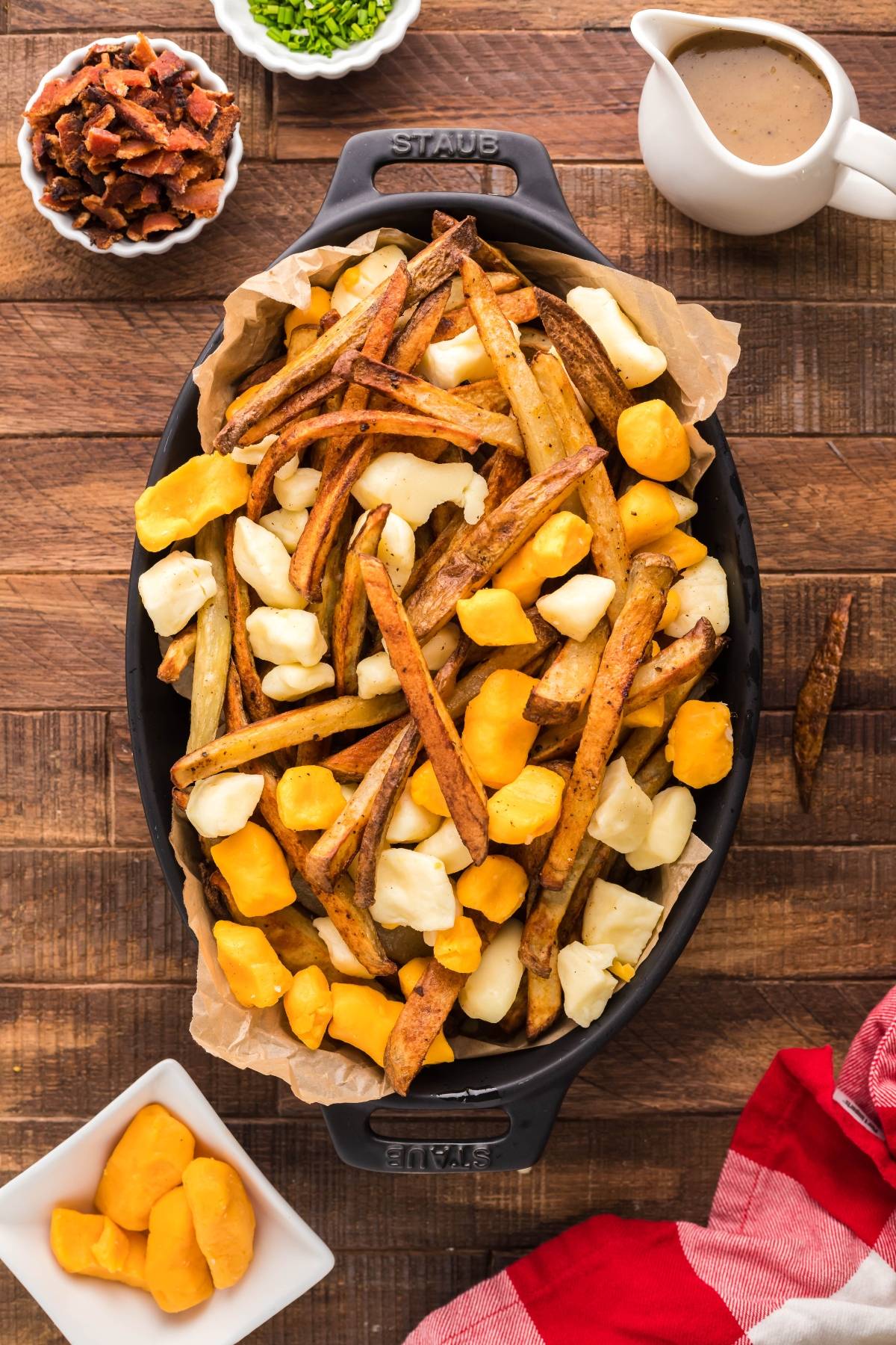 Enjoy this Canadian poutine featuring oven-baked fries and cheese curds, served with the best poutine gravy recipe, chives, and bacon bits for a savory twist on a classic favorite.