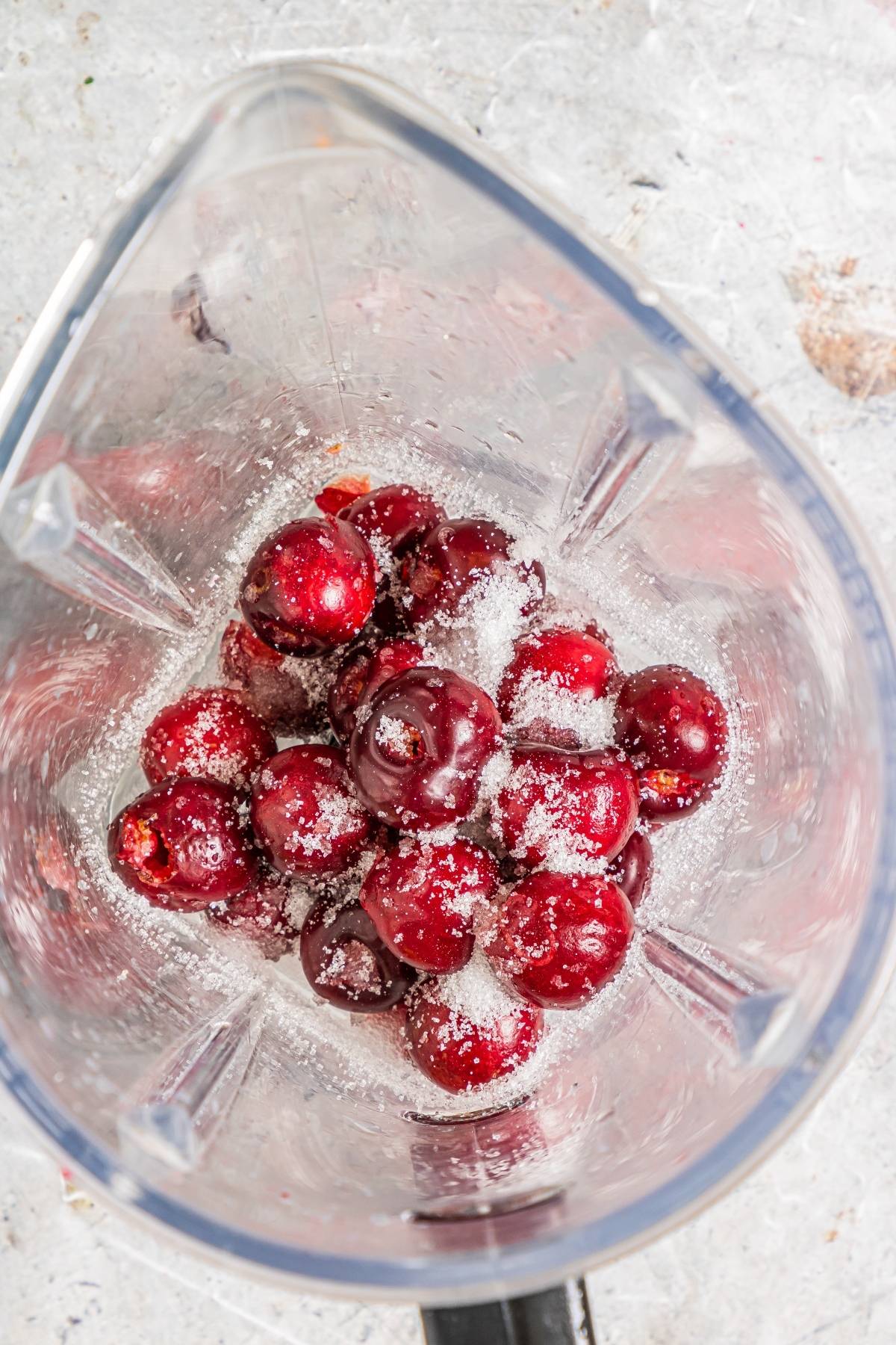 Fresh cherries with sugar in a blender, viewed from above, are ready to be blended for a delicious cherry dessert popsicle—a perfect summer treat recipe.