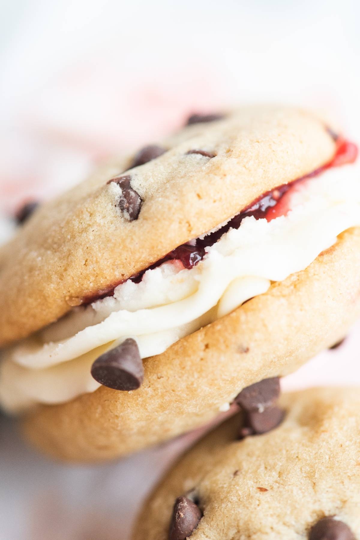 Close-up of a chocolate chip sandwich cookie filled with cream and strawberry jam, showcasing the best filling for sandwich cookies.