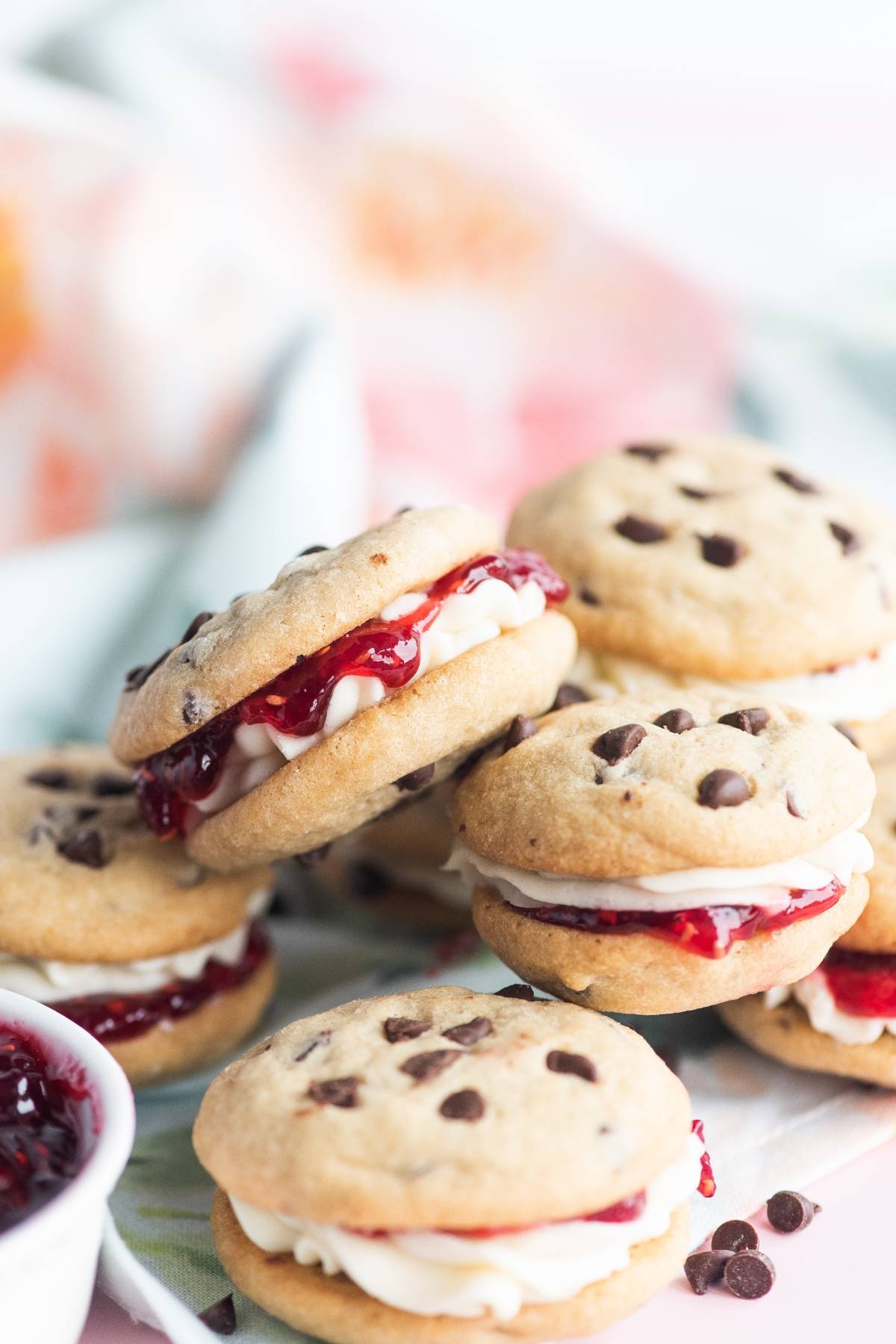 Chocolate Chip Buttercream Sandwiches filled with white frosting and red jam, stacked on a light surface—these are the best sandwich cookies with jam for any sweet craving.