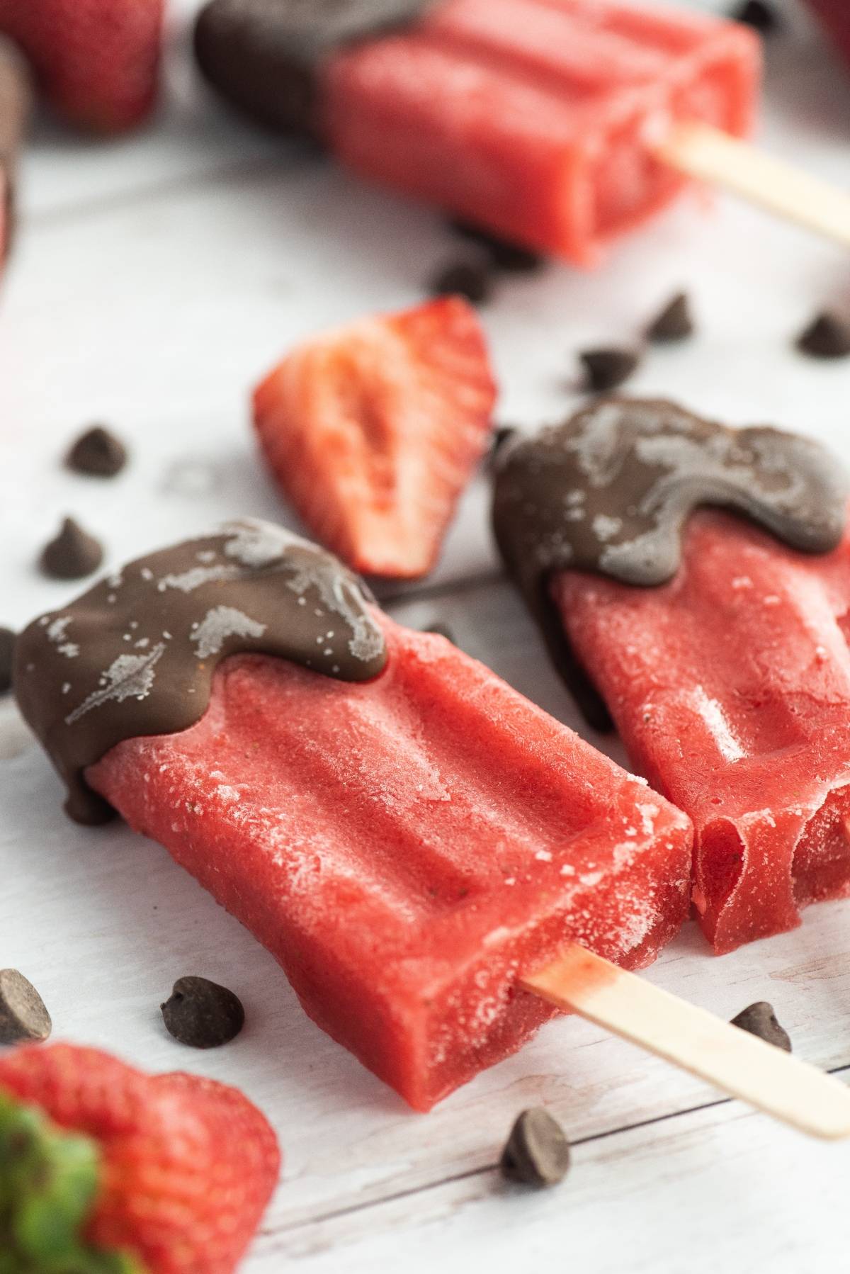 Chocolate Covered Strawberry Popsicles dipped in rich chocolate, surrounded by fresh strawberries and chocolate chips, make easy homemade popsicles perfect for any sweet craving.