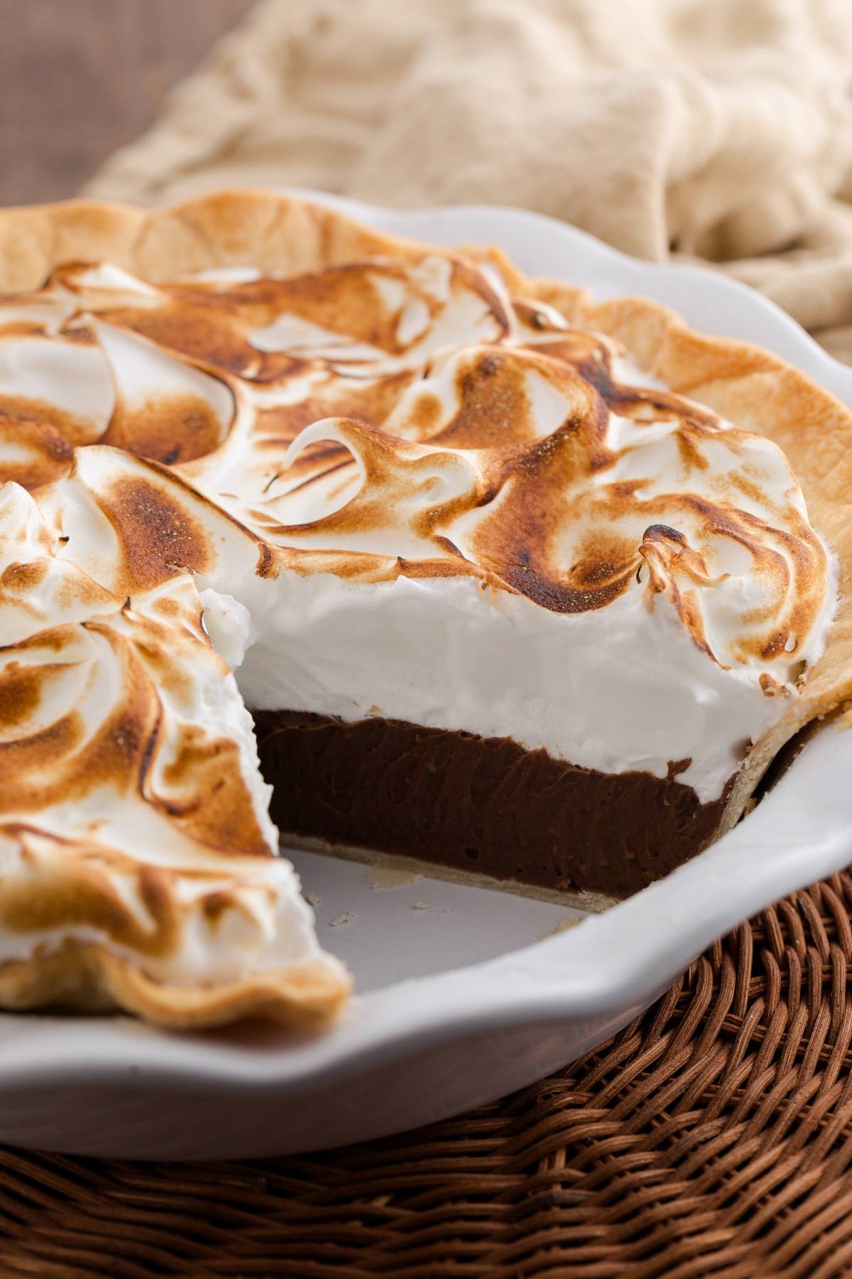 A chocolate meringue pie with a slice missing, showing the chocolate filling and toasted meringue topping.