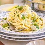 A plate of dirty martini pasta with green olives, cheese, lemon zest, and herbs served on a floral-patterned dish.