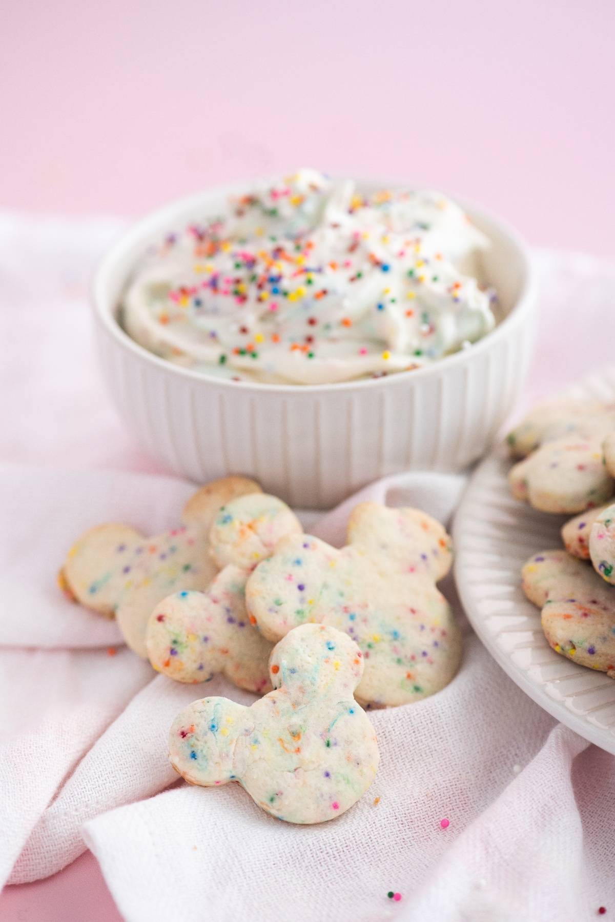 Mickey Mouse-shaped Disney Sugar Cookies with Dip, served alongside a bowl of cream cheese sprinkle dip topped with rainbow sprinkles.