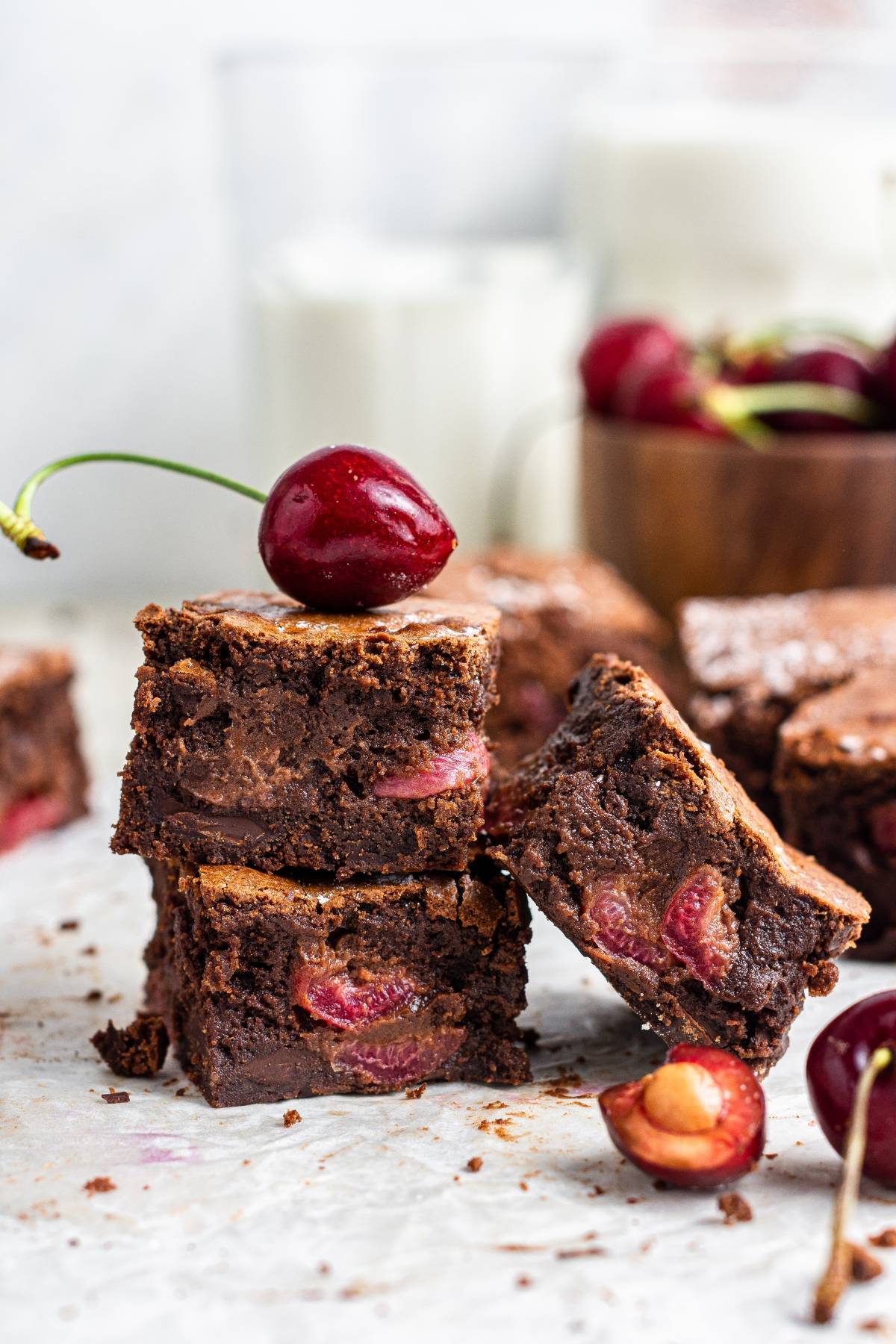 Three stacked fresh cherry brownies with a cherry on top, surrounded by more cherries and brownies—a delicious and easy cherry dessert perfect for showcasing a recipe using fresh cherries.